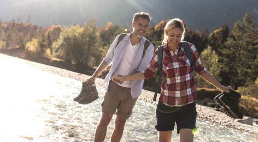 An einem langen Wandertag genießt ein glückliches Paar einen erfrischenden Spaziergang durch einen Fluss