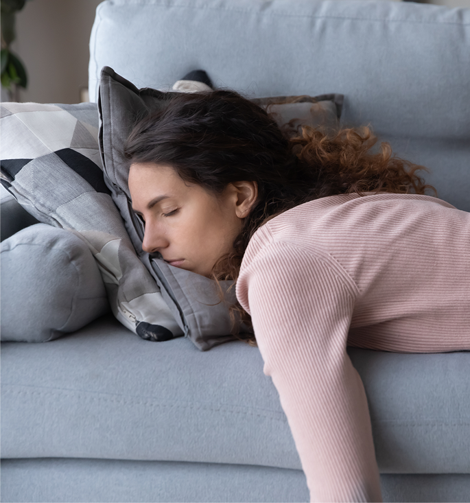 Frau liegt erschöpft auf der Couch