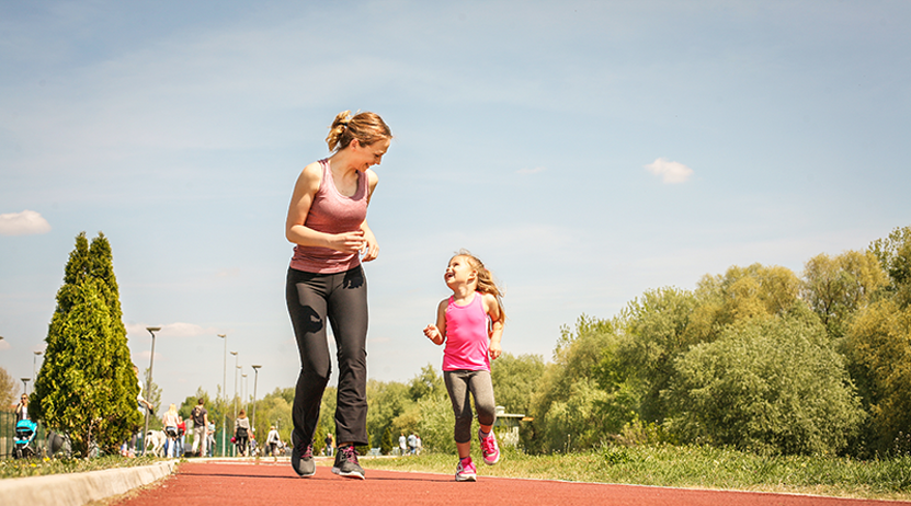 Mutter mit ihrer kleinen Tochter beim Jogging an einem sonnigen Tag